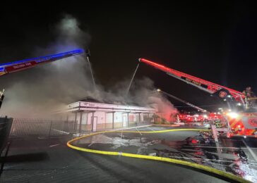 fire trucks spraying water on a building with smoke