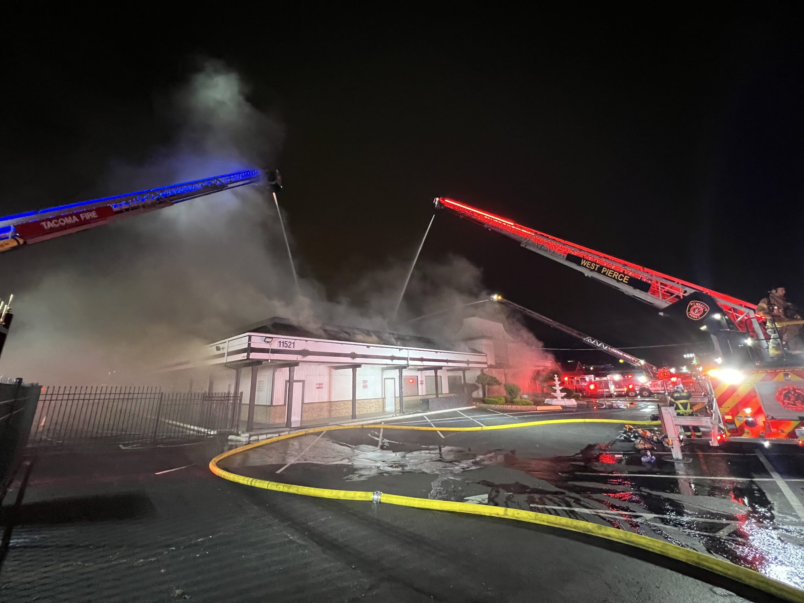 fire trucks spraying water on a building with smoke
