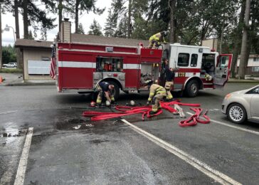 firefighters in front of a fire engine loading hose after a fire incident
