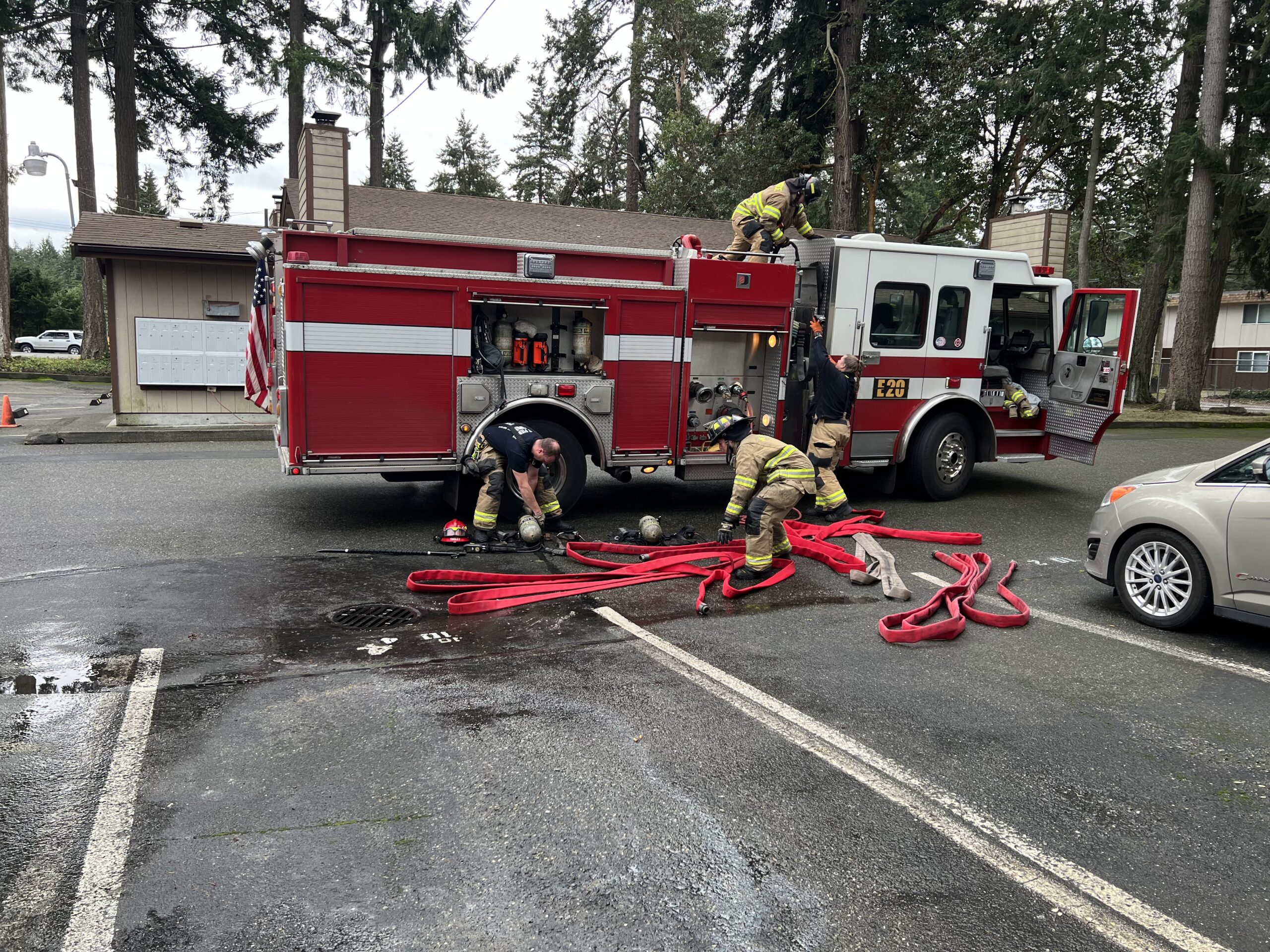 firefighters in front of a fire engine loading hose after a fire incident