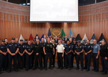 Group photo of firefighters and police officers in front of the flags in lakewood council chambers
